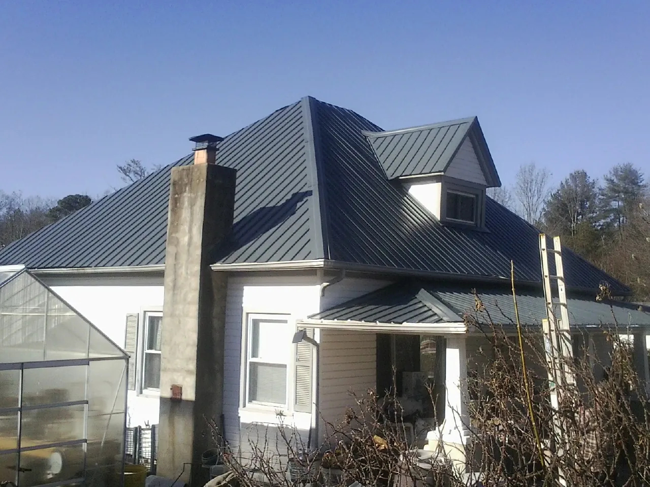 Dark blue standing seam metal roof on a white farmhouse with dormer — Slate & Tile Roof Repair by Roofing Brothers in Tremont