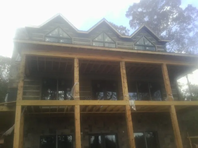 Dormers and porch framing on a large log home under construction — Roof Coating work by our crew in Tremont