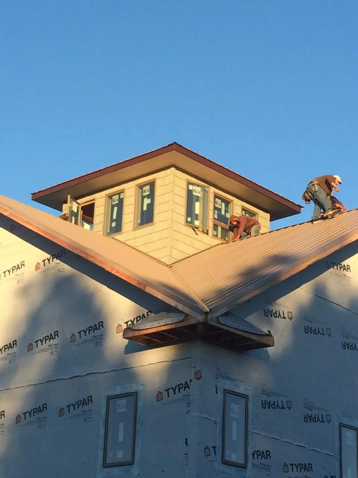 Roofers working around a rooftop cupola on a new metal roof at sunset — Roof Waterproofing in Tremont by Roofing Brothers